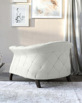 Elegant white loveseat with geometric quilted design on backrest and seating area, featuring dark wooden legs and placed on a textured grey area rug.