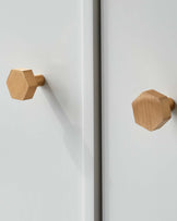 Two modern, minimalistic wooden cabinet knobs in geometric design on a clean, white surface.