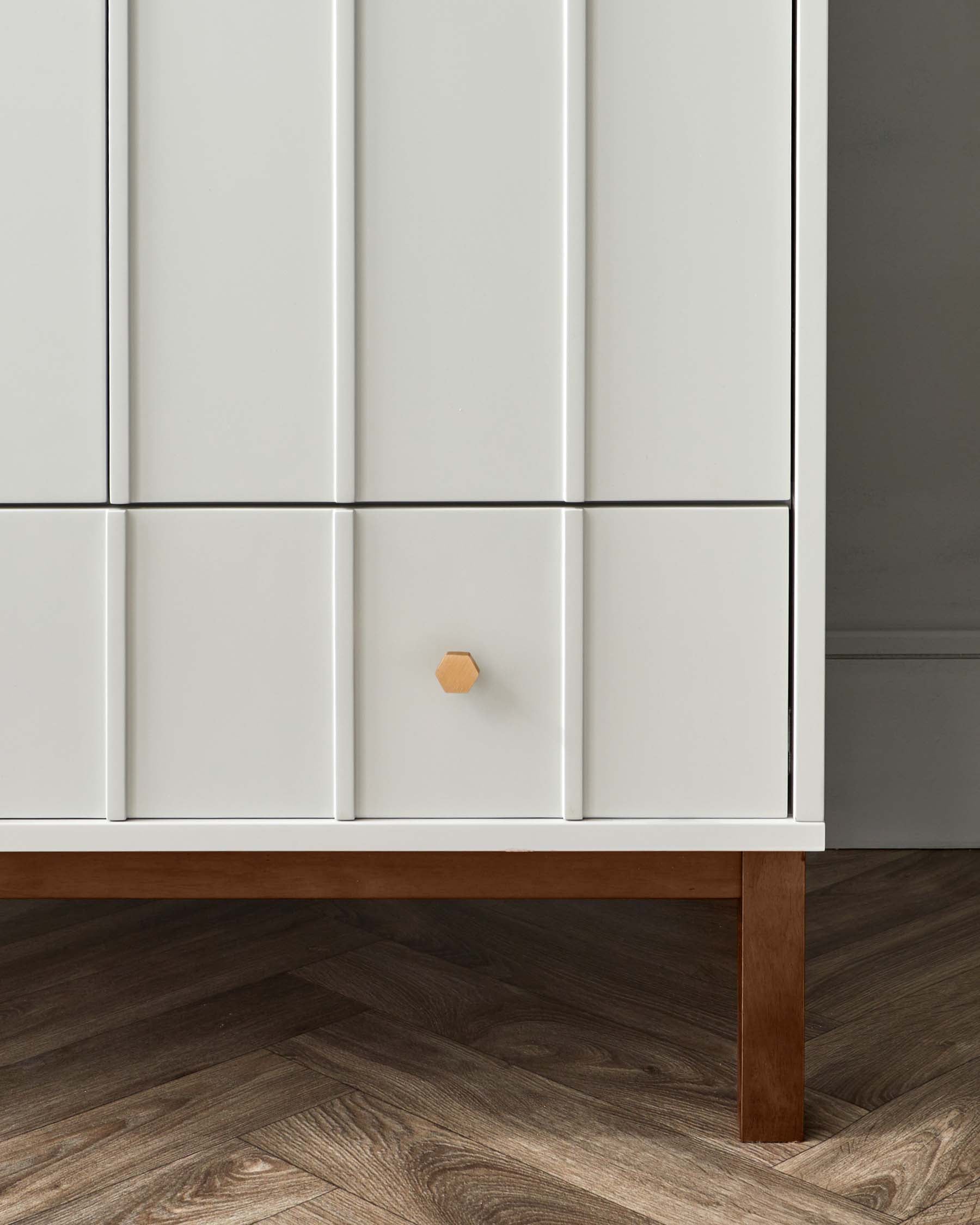 A modern white cabinet with a minimalist design, featuring clean lines, flat panel doors, and a single wooden knob on one of the doors. The piece stands on a short, flat wood base that provides a contrast to the all-white structure.