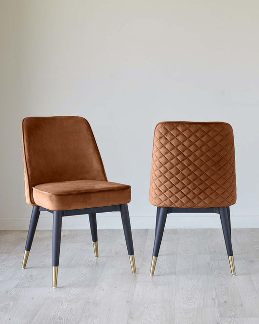 Two elegant dining chairs with dark grey legs tipped with gold accents and upholstered in a plush caramel velvet fabric. The chair on the left features a smooth, plain backrest and seat, while the chair on the right has a quilted diamond pattern backrest. Both chairs have a contemporary design that combines comfort with a sophisticated aesthetic.