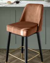 Elegant contemporary bar stool with a rose gold velvet upholstered seat and backrest, featuring quilted detailing, flanked by sleek black legs with gold footrest accents.