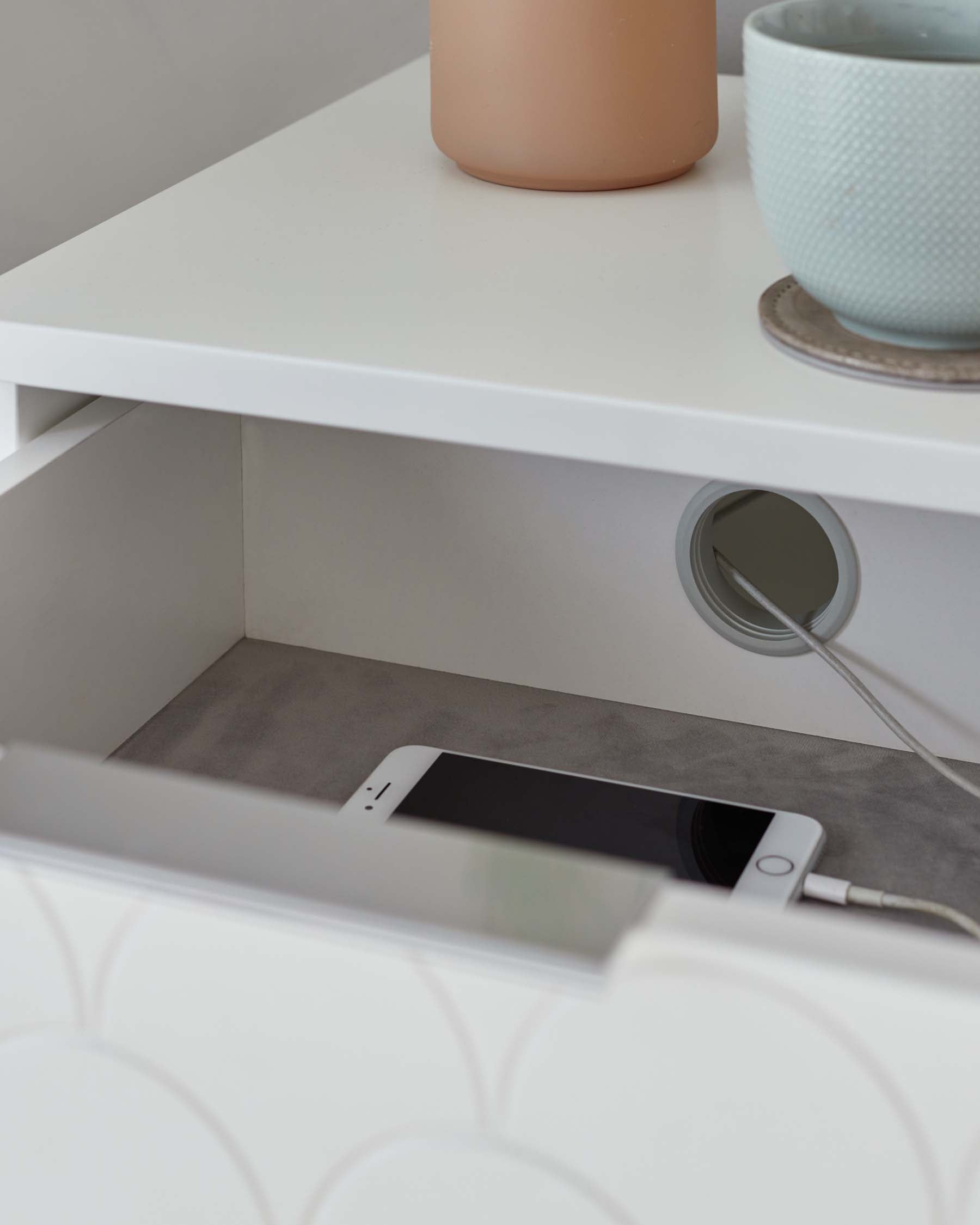 Modern white nightstand with a minimalistic design, featuring an open shelf with a charging cable pass-through for electronic devices.