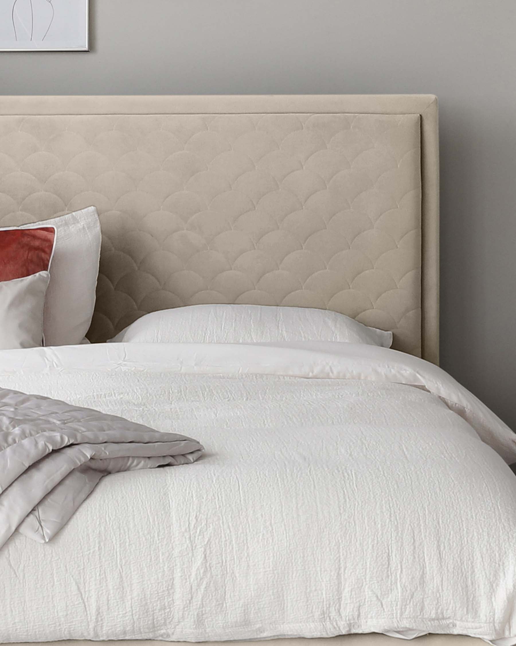 Elegant upholstered headboard with a tufted, scalloped design in a neutral beige tone, paired with a simple white bed linens set atop a presumably matching bed frame (not fully visible).