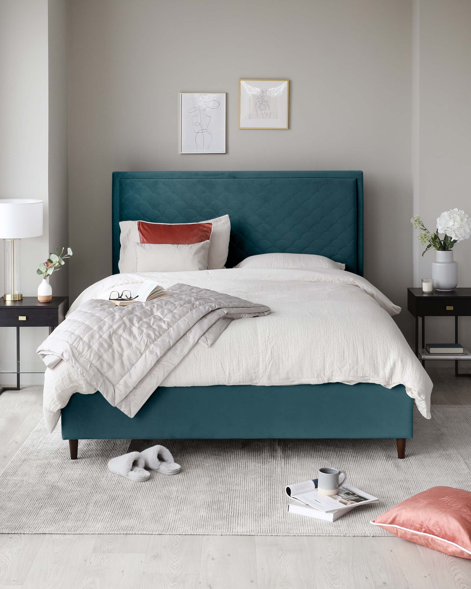 Elegant contemporary bedroom featuring a teal upholstered bed with a tufted headboard, accompanied by a sleek black bedside table with brass accents, and a classic white table lamp with a drum shade. The setting is completed with a soft beige area rug.