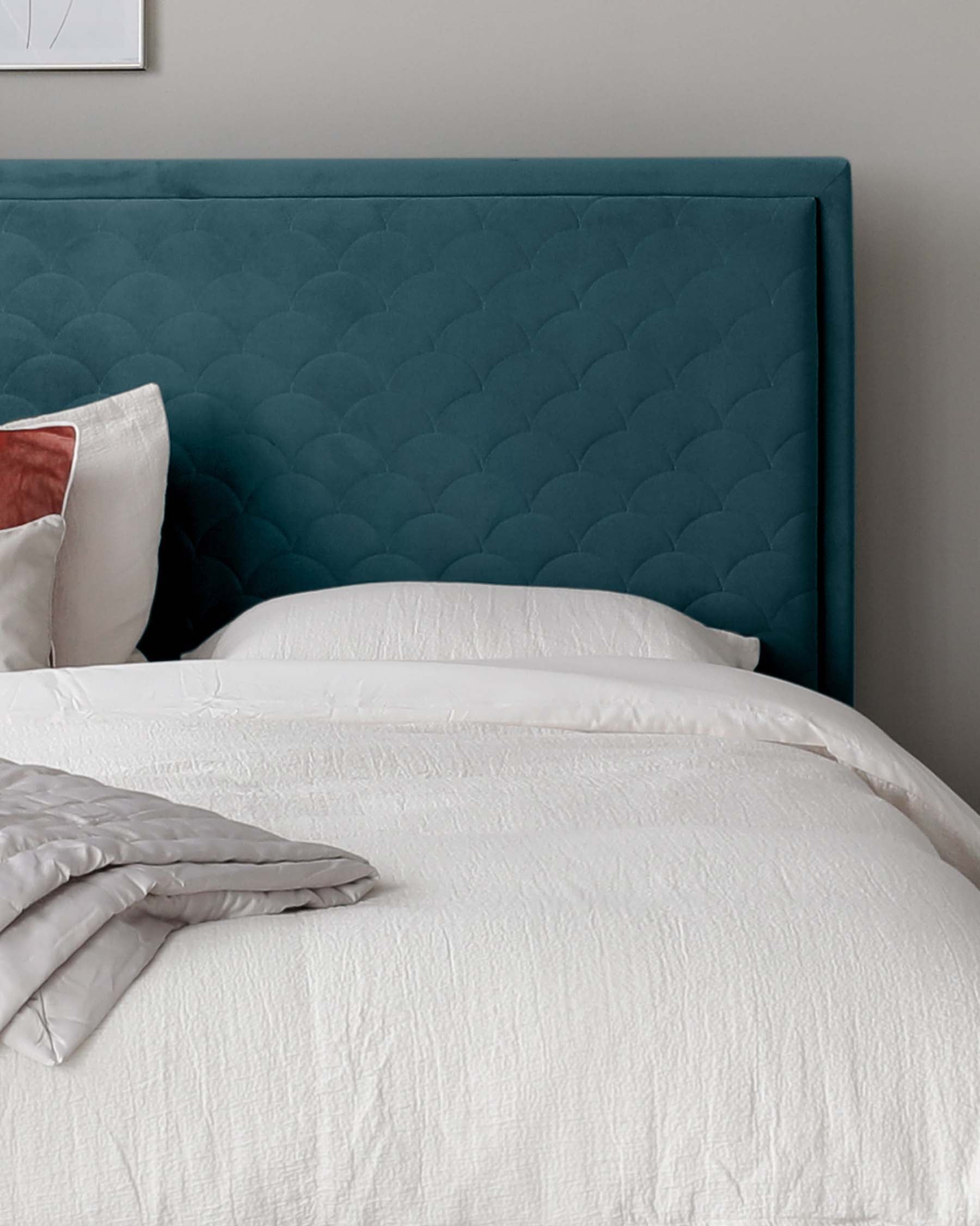 Elegant upholstered bed featuring a teal tufted headboard with a geometric pattern, framed by simple, clean lines. The bed is dressed with crisp white bedding and a folded grey comforter at the foot, creating a modern and sophisticated bedroom aesthetic.