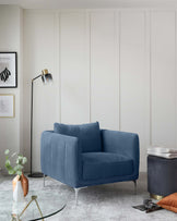 A contemporary blue velvet loveseat with vertical channel tufting and sleek metallic legs; a round glass-top side table with a gold-finished base; and a round, dark blue upholstered ottoman with a hidden storage feature and a brass base.