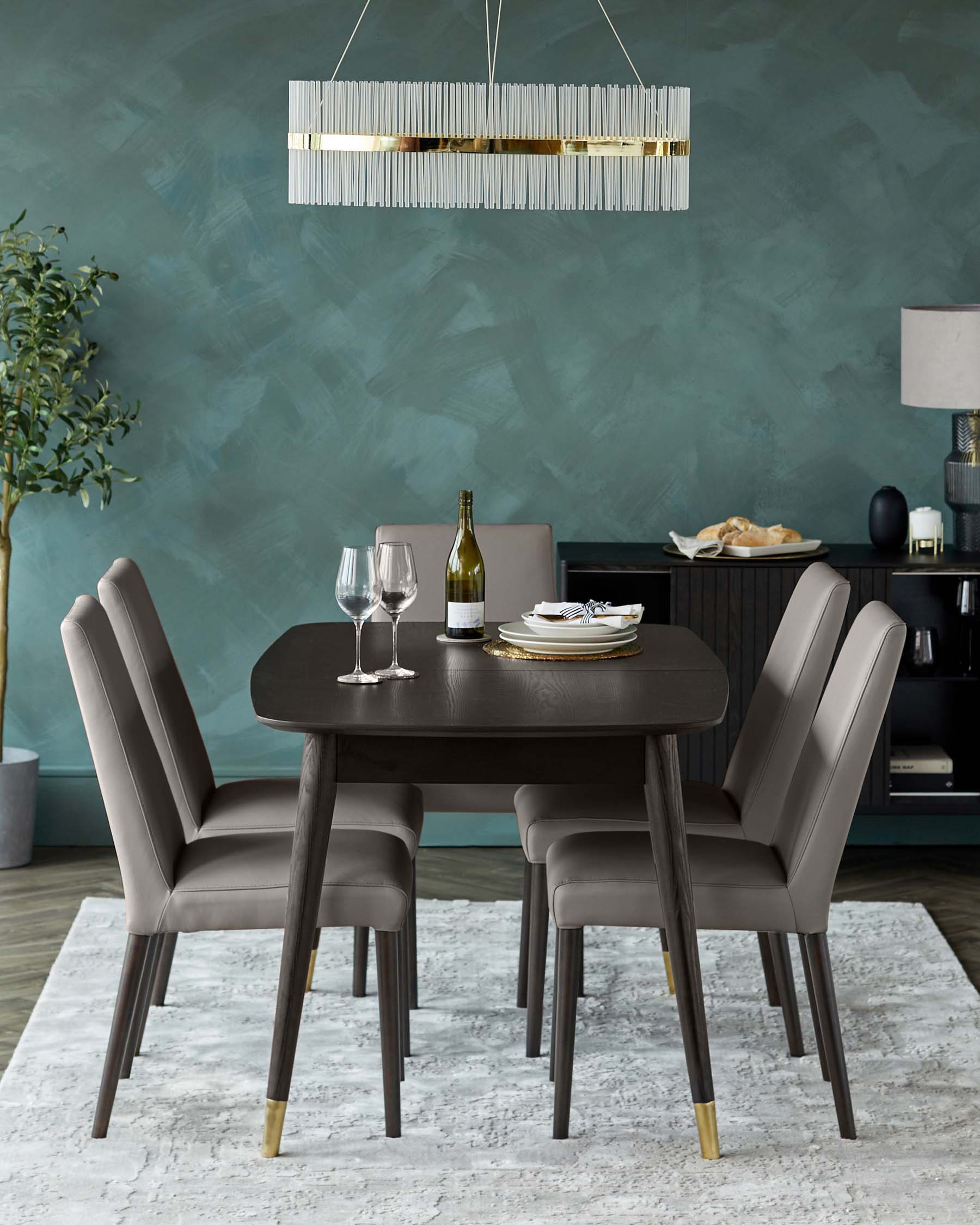 Modern dining set with a dark wood round table and four sleek, upholstered chairs with vertical stitching and subtle gold accents on the legs.