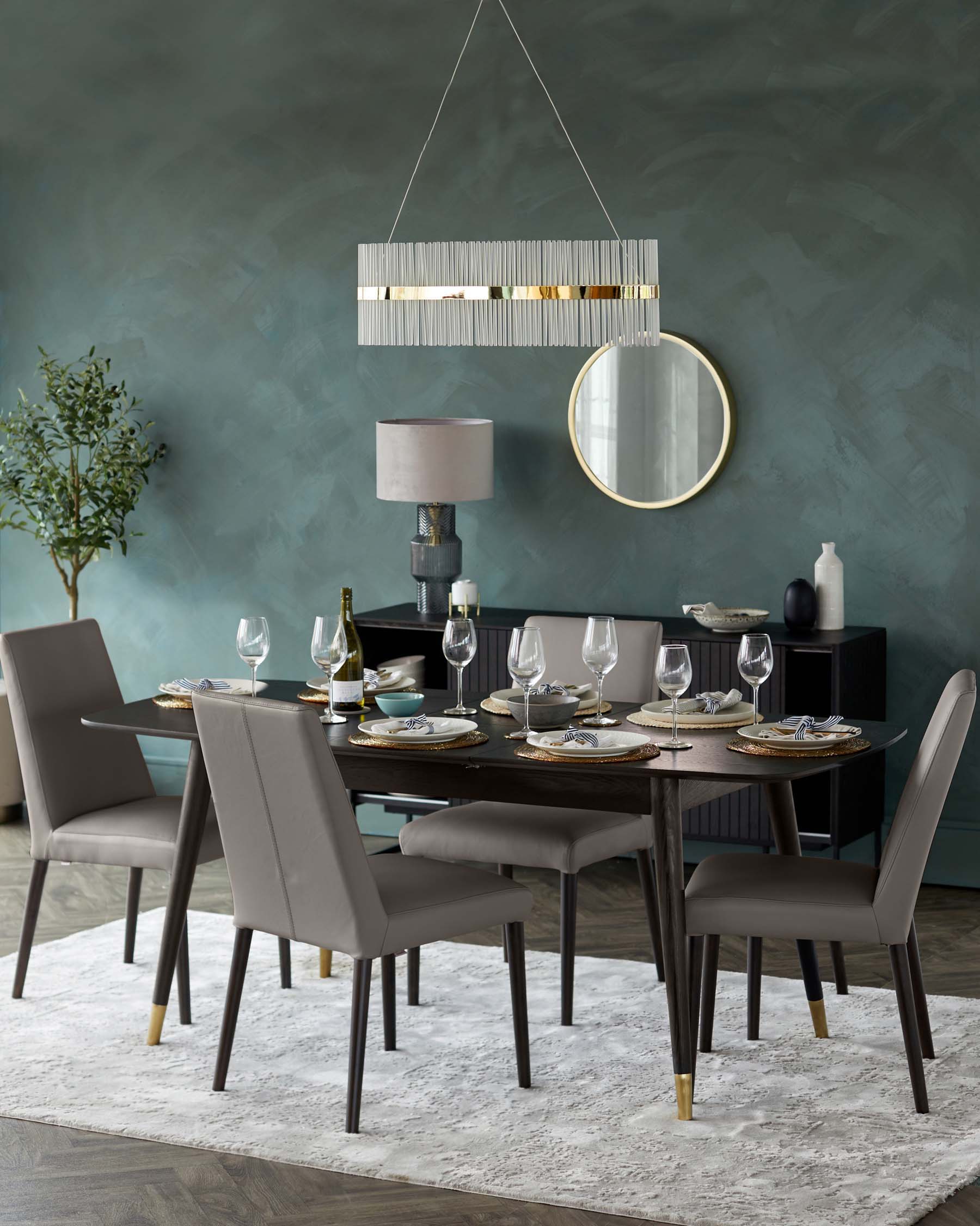 Elegant dining room setup featuring a contemporary rectangular wooden table with tapered legs accented with brass tips. Six matching upholstered dining chairs with slender legs and a modern silhouette complement the table. The setting is on a textured light grey area rug.