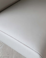 Close-up of a contemporary light grey leather bench with a fine stitched seam, showcasing its textured upholstery and clean, minimalistic design.