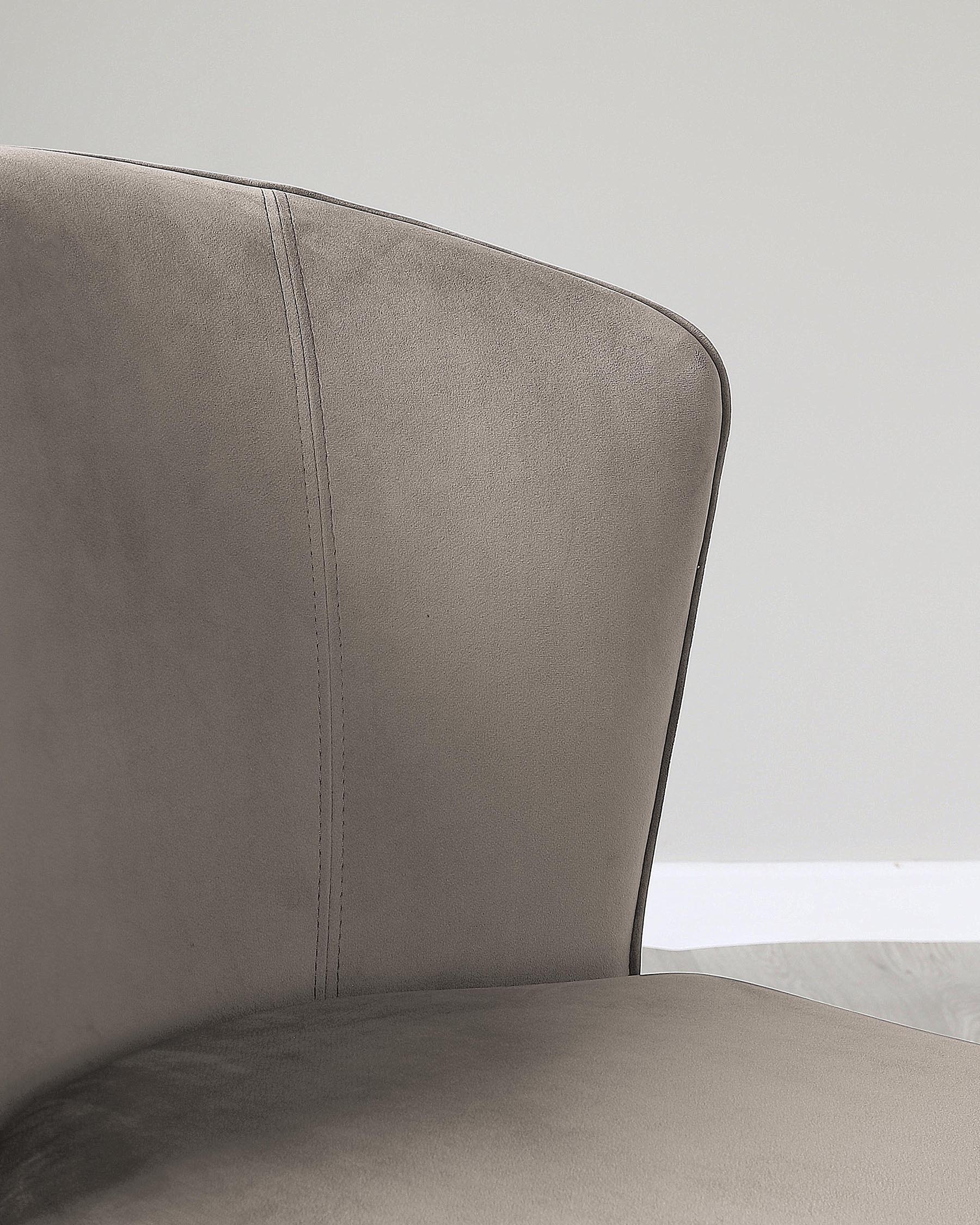 Close-up of a modern taupe upholstered chair with a curved backrest and a visible seam detail, featuring a soft fabric texture, positioned against a neutral background.