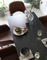 Elegant dining room setting featuring a modern rectangular table with a black marble finish and rounded brown leather dining chairs with a smooth, high backrest.