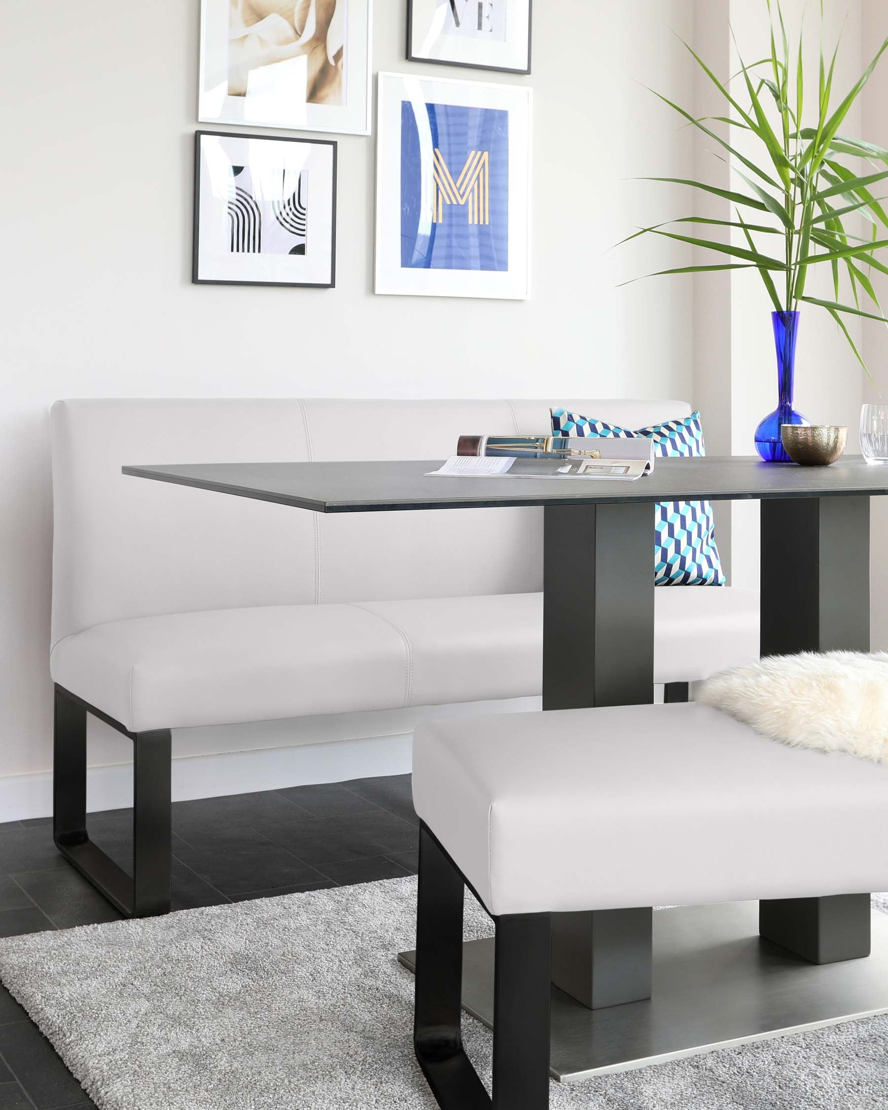 Modern minimalist furniture set against a neutral backdrop, featuring a sleek white upholstered bench with dark metallic legs and a matching low-rise coffee table in a contrasting dark finish. Both are styled atop a textured grey area rug, complementing the contemporary room aesthetic.