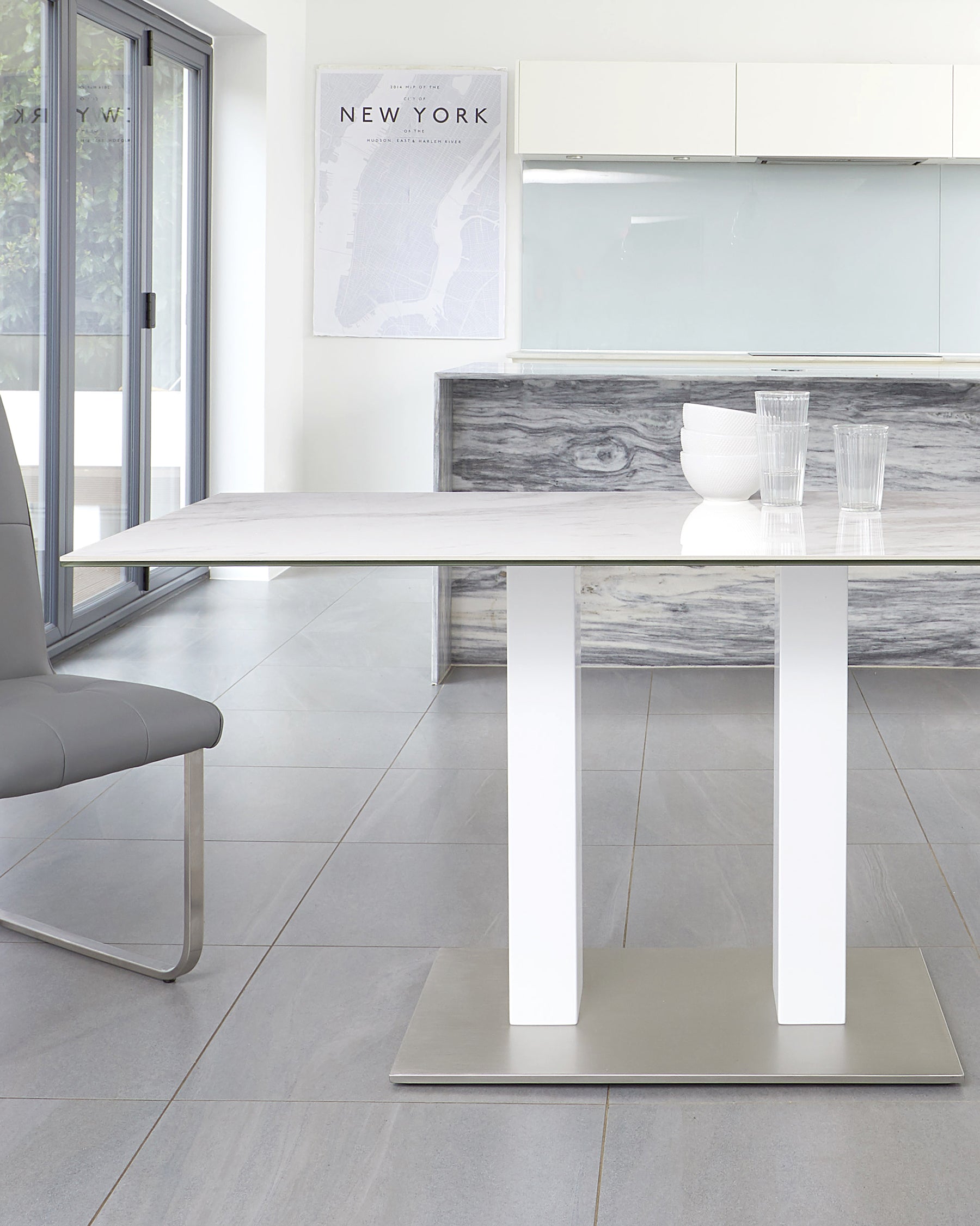 A sleek white dining table with a marble top and stainless steel base, paired with a modern gray chair.