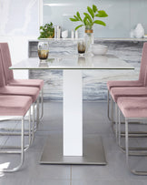 Modern dining set featuring a sleek rectangular glass-top table with a solid white pedestal base and a metallic silver platform. Accompanied by four contemporary dining chairs with soft pink upholstery and lustrous silver metal frames in a cantilever design that adds a floating sensation.