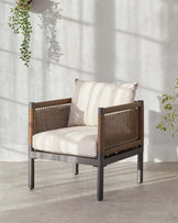 Modern single-seat armchair with a sleek dark metallic frame, woven brown sides and back, and plush off-white cushioning, situated in a well-lit space with soft shadows.