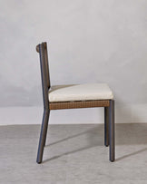 A modern chair with a minimalist design, featuring a dark frame and light beige upholstered seat with textured back support, set against a neutral background.