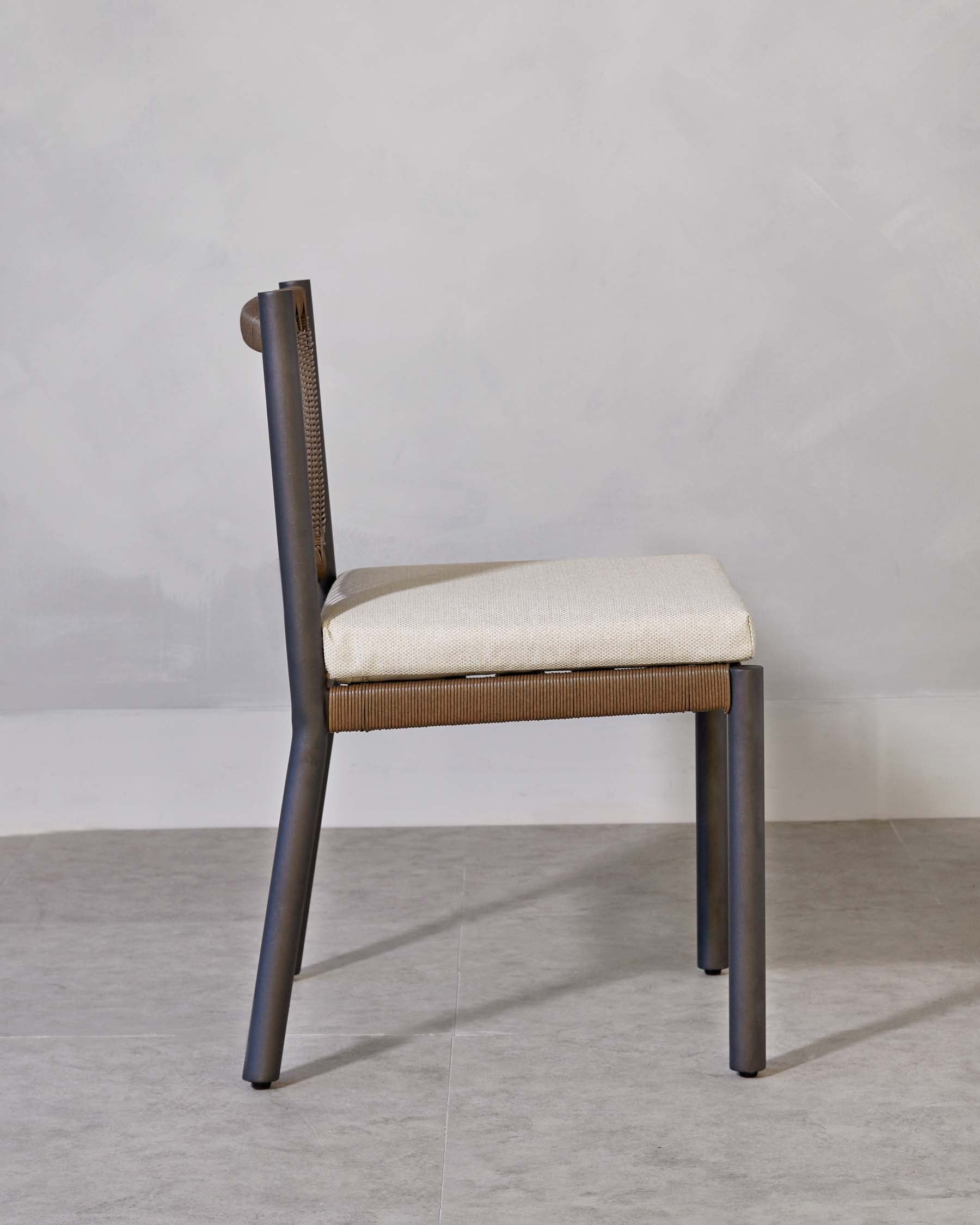 A modern chair with a minimalist design, featuring a dark frame and light beige upholstered seat with textured back support, set against a neutral background.