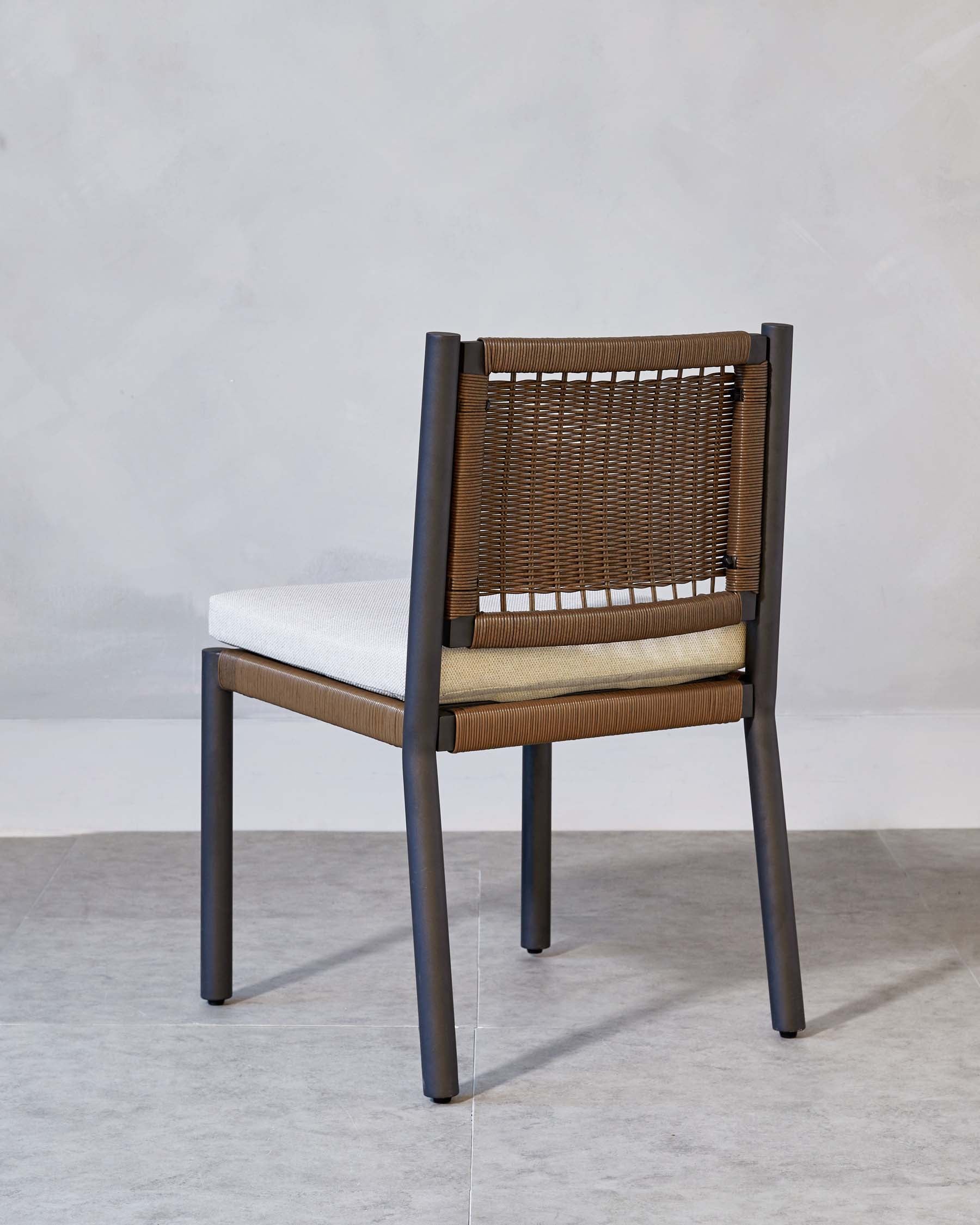 Modern dining chair with dark wooden frame, light upholstered seat, and brown woven backrest.