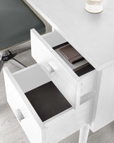 Modern white office desk with open drawers showcasing minimalist design and a sleek finish, complemented by a stylish grey upholstered chair with a chrome base.