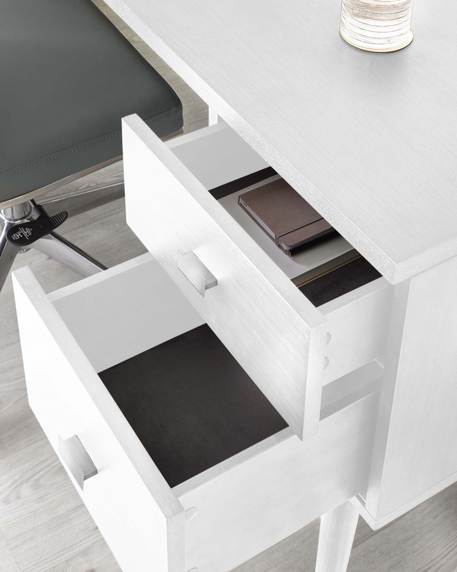 Modern white office desk with open drawers showcasing minimalist design and a sleek finish, complemented by a stylish grey upholstered chair with a chrome base.