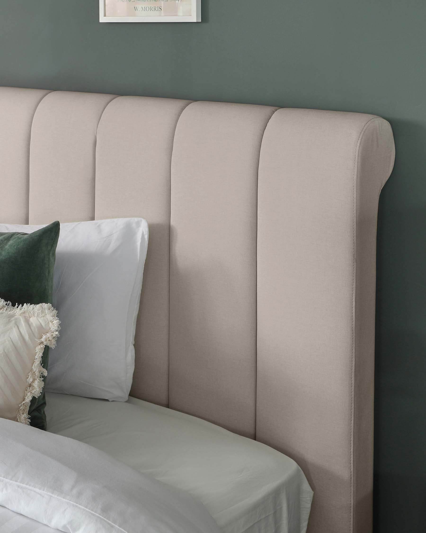 Elegant upholstered headboard in a neutral colour with vertical channel tufting and a gentle curved top edge, providing a soft backdrop to a bed with white linens and a velvet green throw pillow.