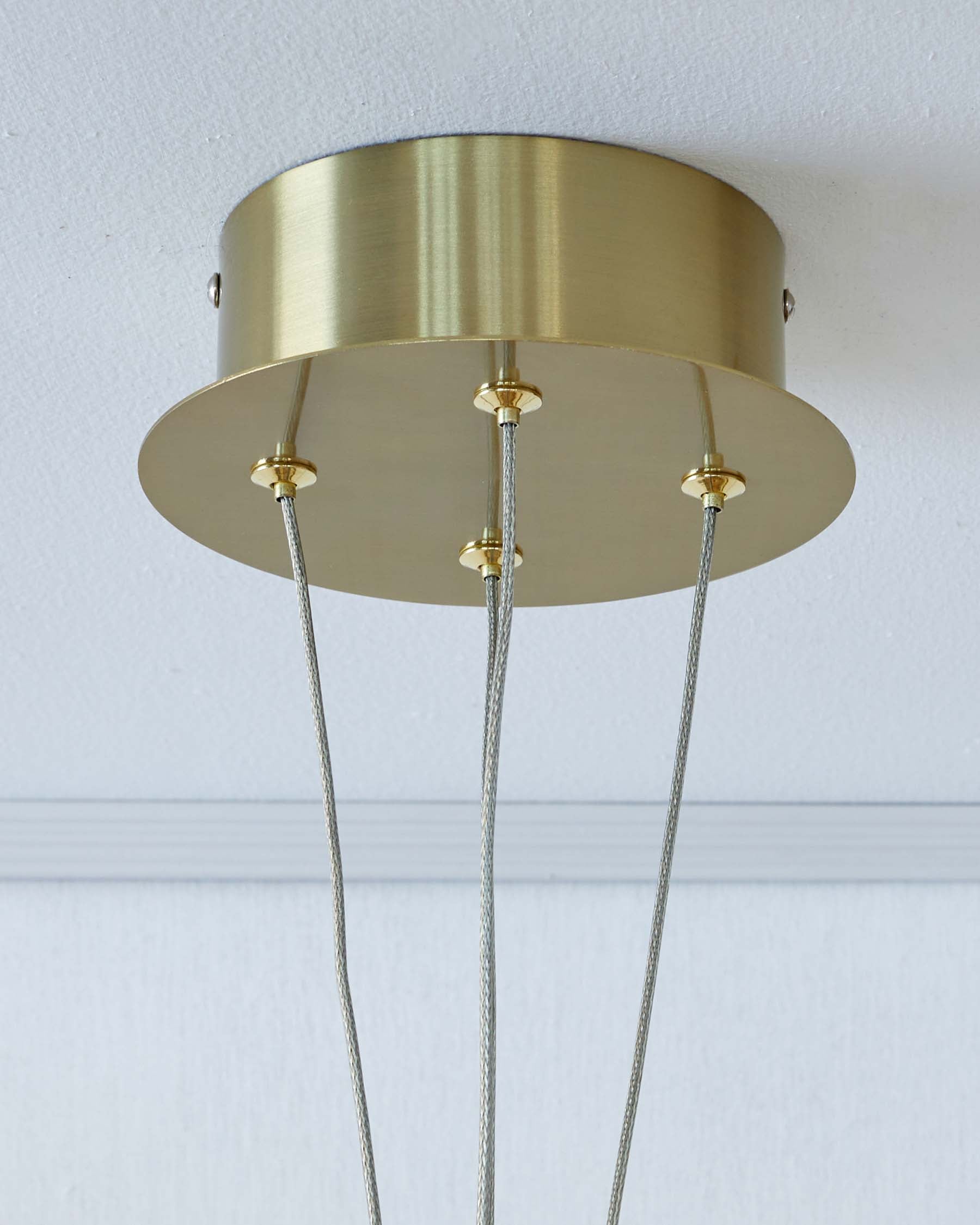 Modern brass ceiling fixture with a minimalistic design, featuring multiple suspended cables.