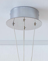 Contemporary ceiling-mounted light fixture with a metallic silver cylindrical canopy, a transparent circular glass shade, and three supporting cables.