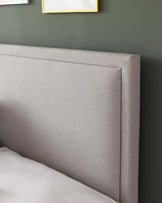 A modern heathered grey upholstered headboard with clean lines and a subtle stitching detail, presenting a sleek and contemporary look for a bedroom setting.