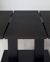 Modern dark-stained wooden extendable dining table with visible metallic hinges on the sides, featuring a thick rectangular top supported by sturdy block legs.