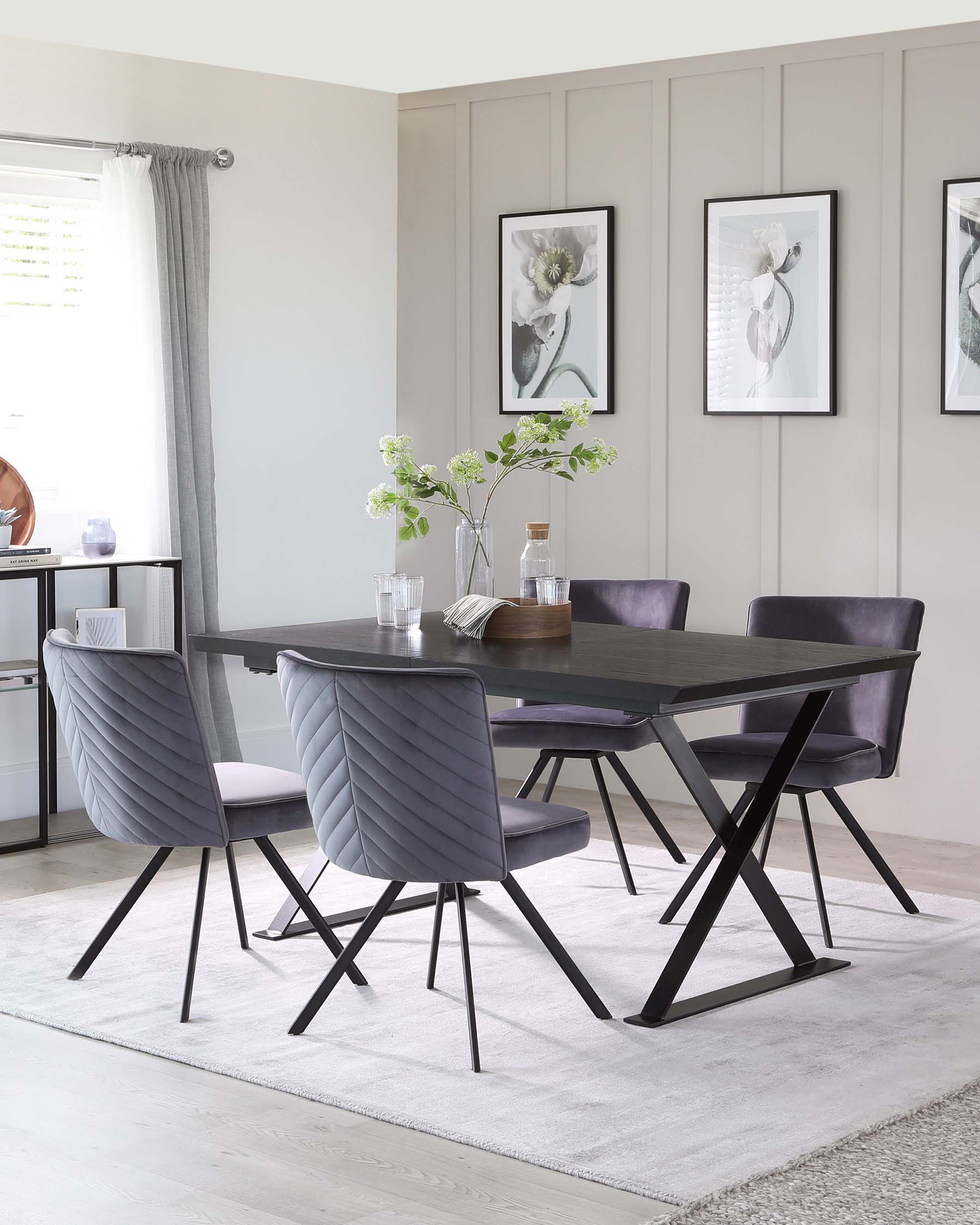 A modern dark wooden dining table with a rectangular top and unique crisscross black metal legs. The table is surrounded by four elegant upholstered dining chairs in a soft grey fabric with a quilted backrest design and black metal legs. A neutral-toned rug underlays the dining set.