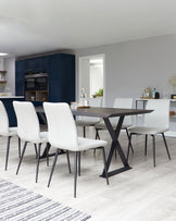 Modern dining room featuring a rectangular dark wood table with an X-shaped metallic base, paired with six contemporary white upholstered chairs with slim black metal legs. A striped area rug lies partially beneath the table set.