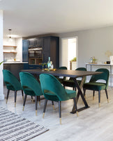 Elegant contemporary dining set featuring a rectangular dark wood table with a unique V-shaped leg design in a contrasting black and brass finish. Six plush velvet dining chairs in a rich forest green colour, with slim tapered legs tipped with brass accents, complement the table. The set offers a sophisticated, luxurious addition to any modern dining space.