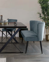 A modern dining set with a sleek black table and plush teal chairs featuring geometric stitching and slender black legs.