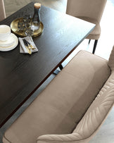 Modern dark wood dining table with a textured surface accompanied by elegant taupe upholstered chairs with vertical stitching detail on the backrest.