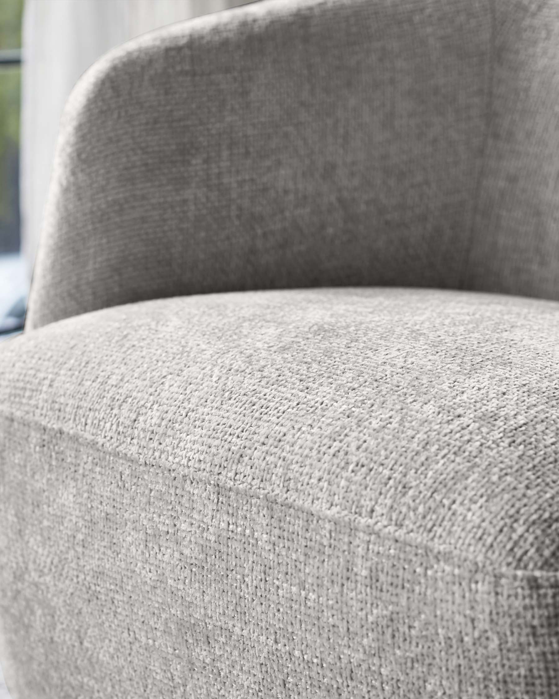 Close-up of a contemporary armchair with textured grey upholstery.