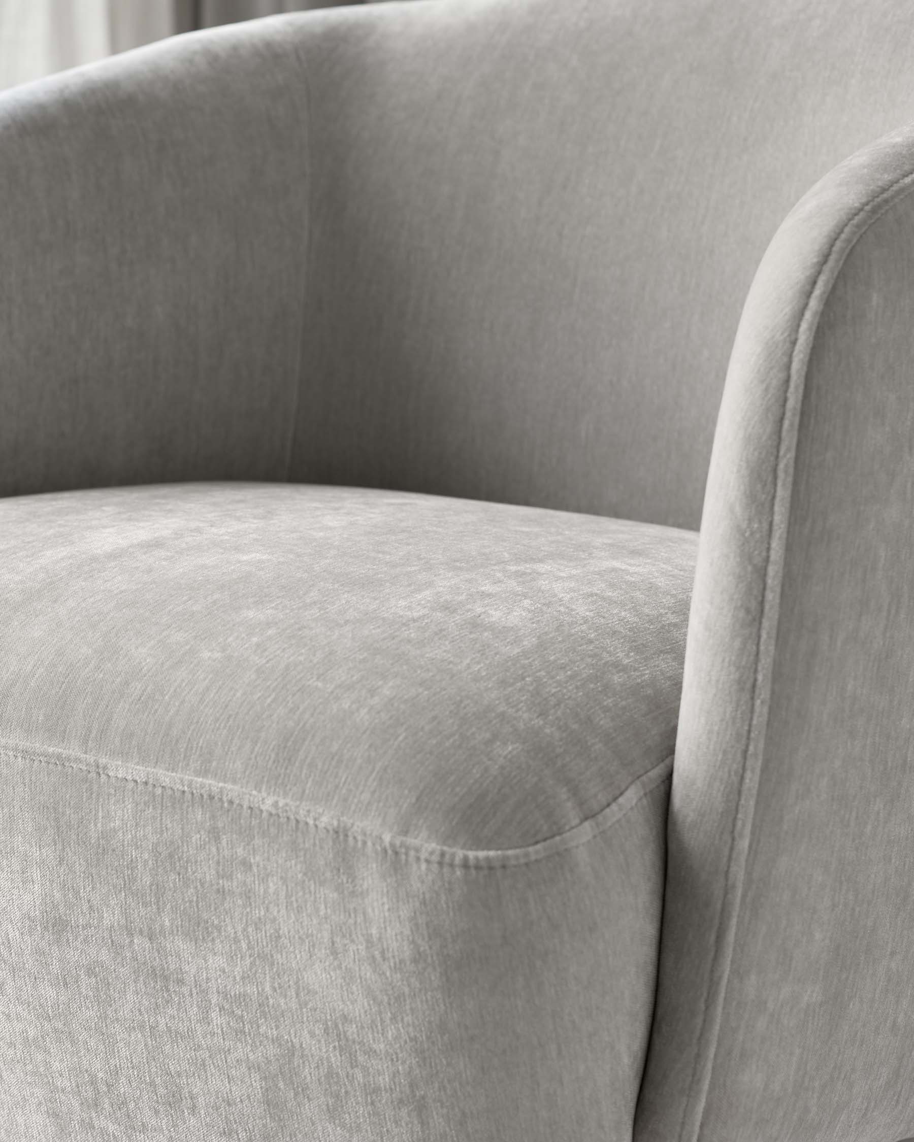 Close-up view of a contemporary, grey upholstered sofa featuring a smooth, curved backrest and a single cushion with neat, visible stitching lines, showcasing minimalist elegance and a soft texture.