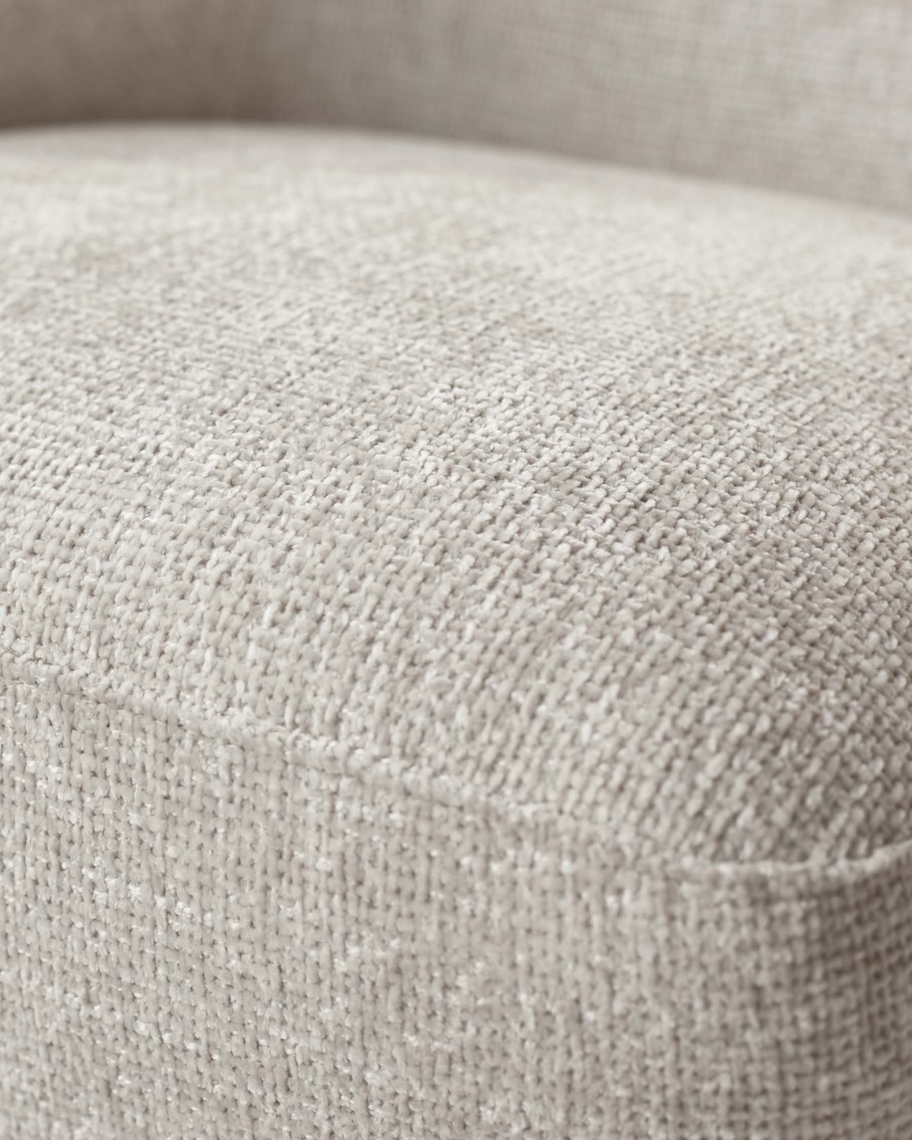 Close-up texture detail of a beige upholstered fabric armchair, highlighting the weave and fabric quality.