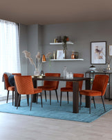 Modern dining room with a rectangular dark wood table and six velvet upholstered chairs in burnt orange. The chairs feature channel tufting and black metal legs. A light blue area rug lies beneath the table set, and on the wall are two white floating shelves displaying decorative items.