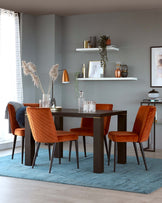 Elegant dining room setup featuring a modern rectangular dark wood table flanked by six burnt orange upholstered dining chairs with vertical channel tufting. The table and chairs rest on a pale blue area rug, creating a contrasting yet harmonious colour palette.