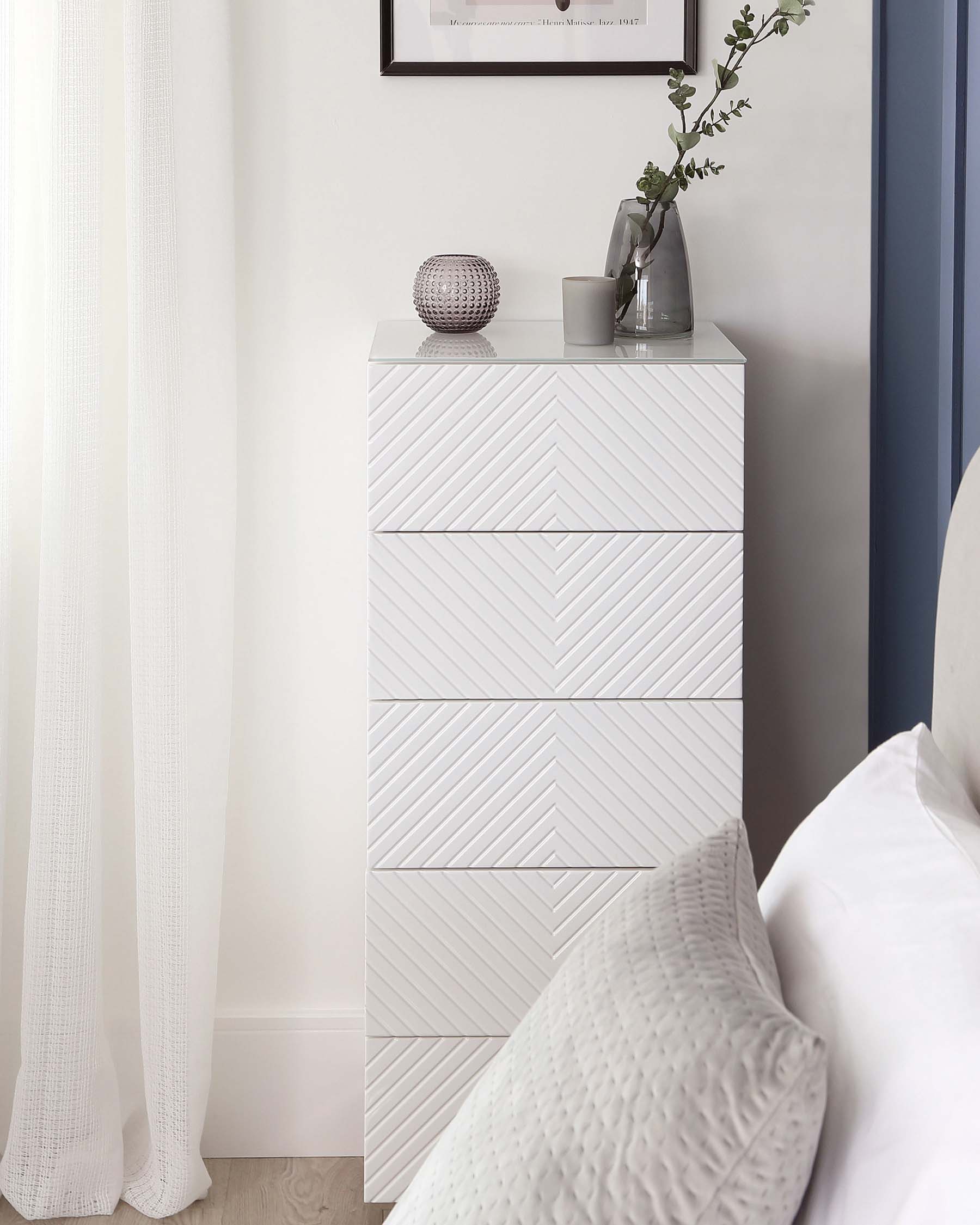 A contemporary white tallboy dresser with a textured chevron pattern on the drawer fronts.