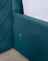 Close-up view of a modern teal upholstered bed frame with a tufted headboard and a smooth footboard, featuring clean lines and a plush finish.