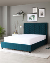 Teal upholstered platform bed with a tall, plush, chevron patterned headboard, paired with a matching teal side table featuring a white lamp and decorative elements. A modern white floating shelf adorns the wall above.