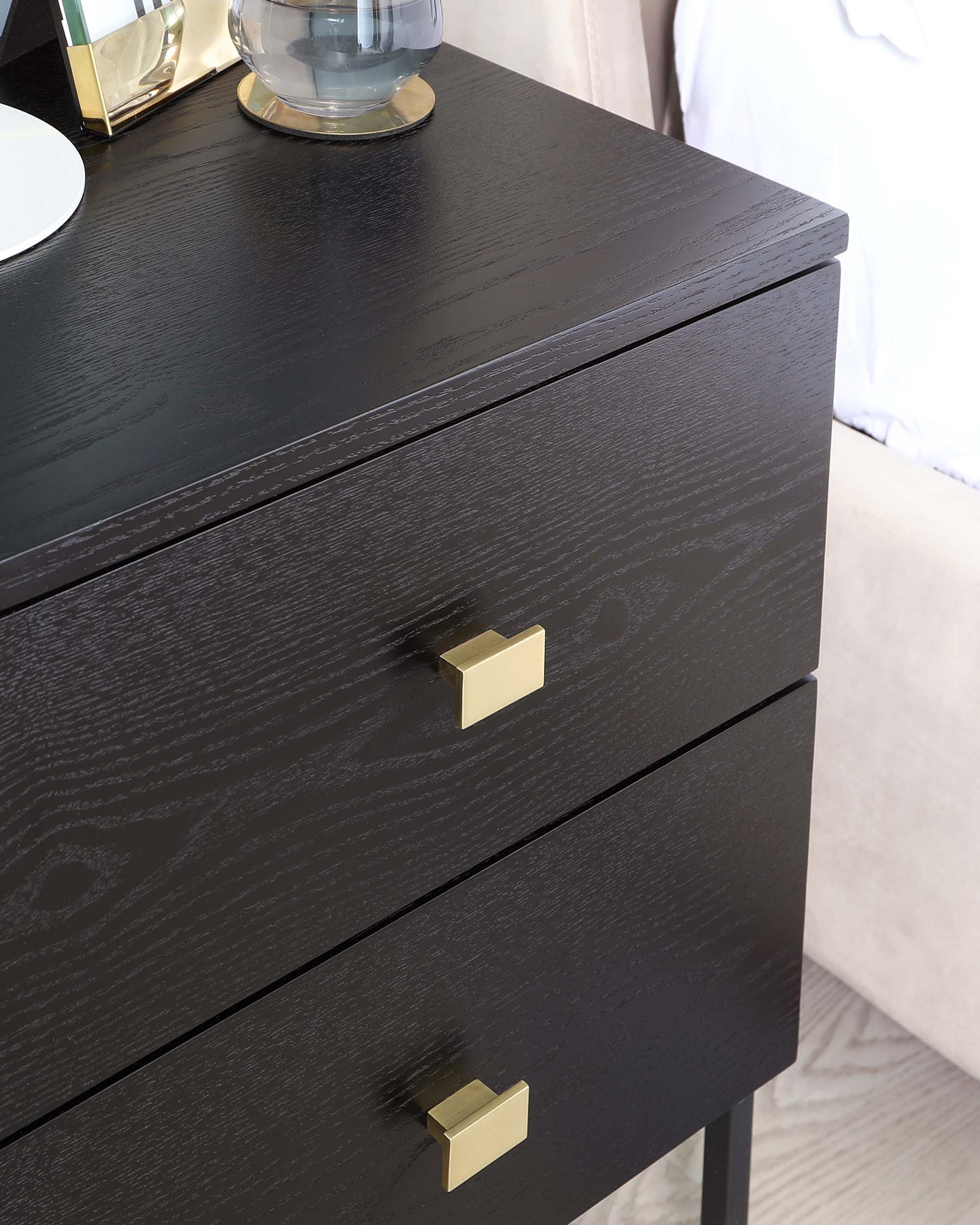 A contemporary black wooden nightstand with a textured finish, featuring two drawers and brass rectangular pull handles.