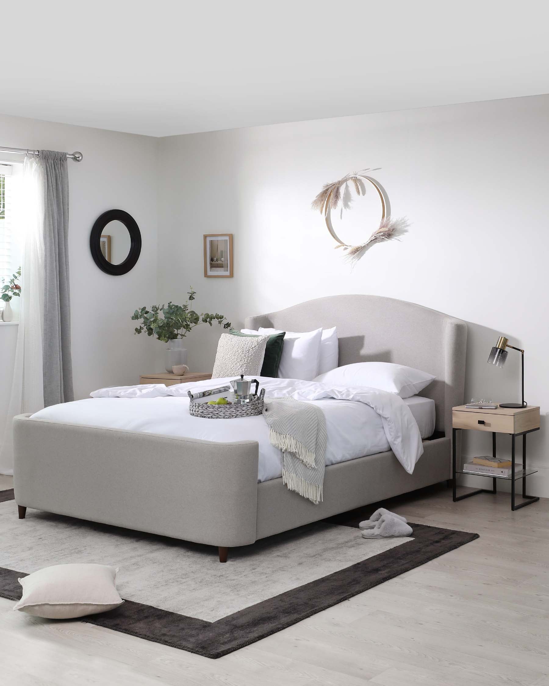 Modern upholstered king-size platform bed in light grey fabric, featuring a curved headboard and low footboard design, with angled wooden legs. Beside the bed is a minimalist rectangular nightstand with a natural wood finish and open shelving, paired with a black metal frame accent lamp with an adjustable arm.