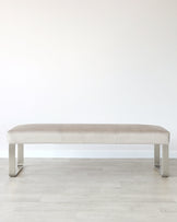 Modern beige bench with a sleek metal frame, featuring a smooth upholstered seat and minimalist design.