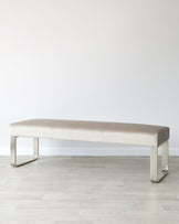 Sleek, modern bench with a soft beige upholstered seat and minimalist metallic legs, perfect for any contemporary space.