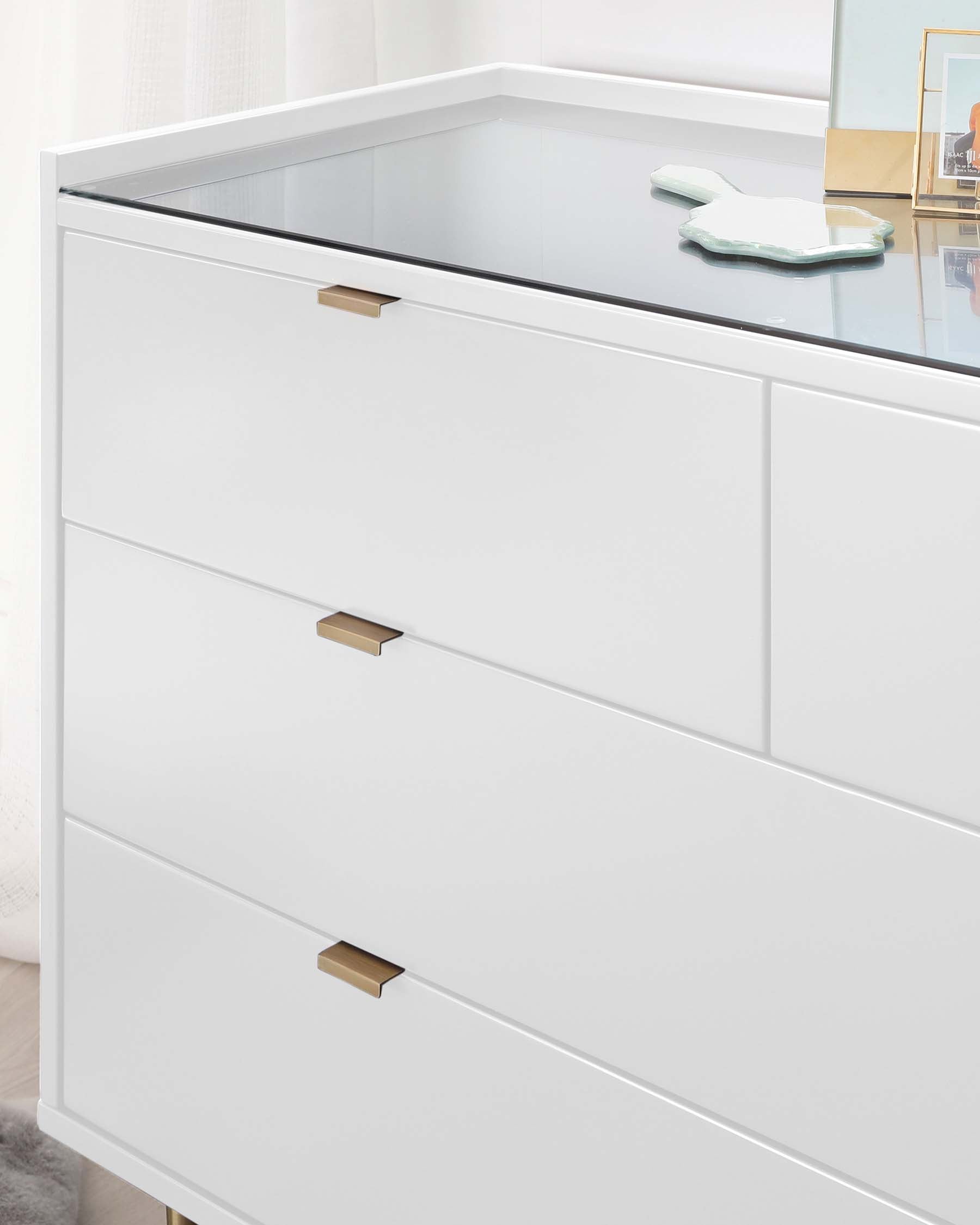 Modern white three-drawer dresser with a sleek design featuring a clear glass top surface and brushed metal handles.