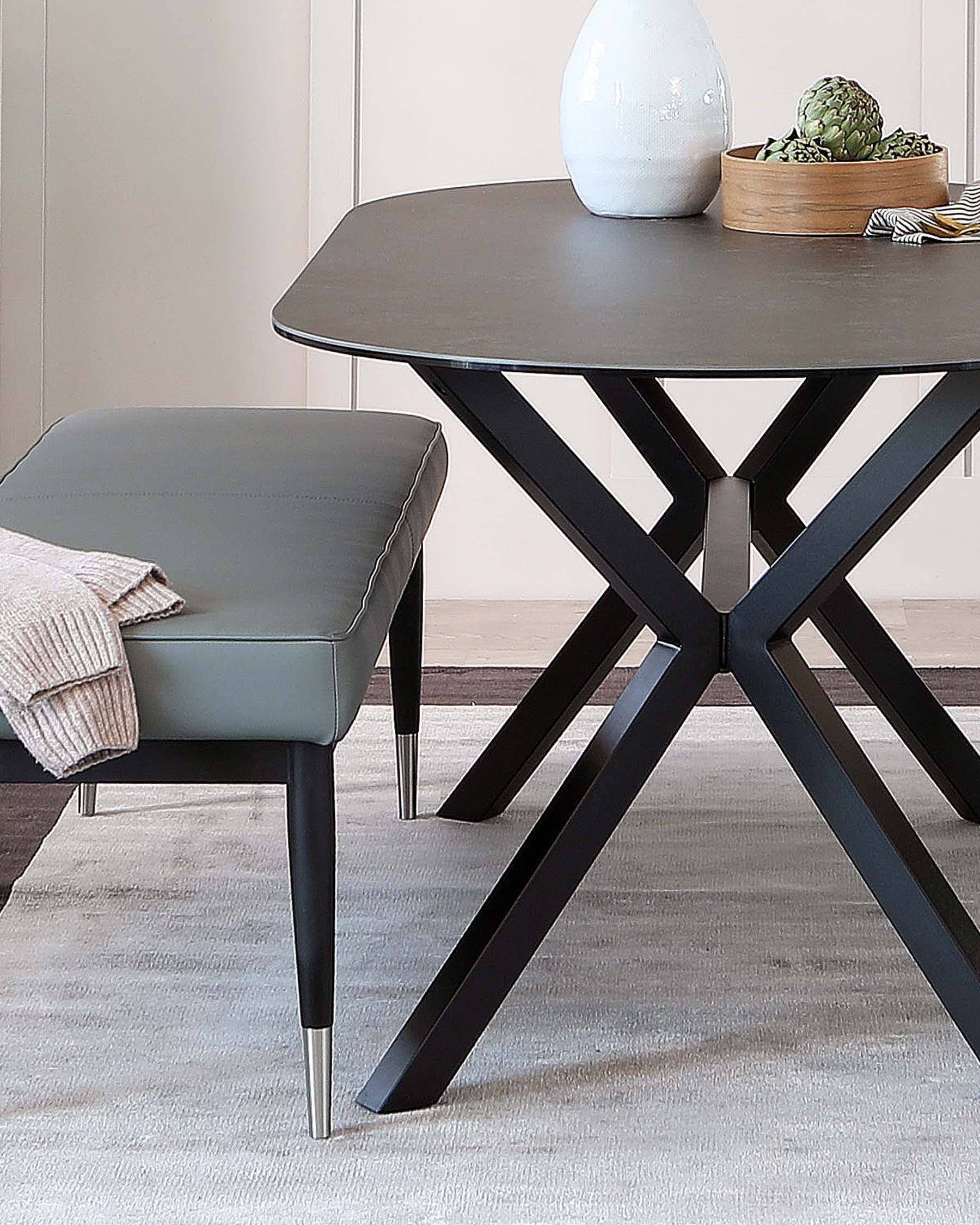 A contemporary dark-stained round wooden dining table with a unique star-shaped base, alongside a light grey upholstered dining chair with black tapered legs finished with metallic tips, placed on a neutral-toned area rug. The table is adorned with a large white vase and a wooden bowl containing greenery.