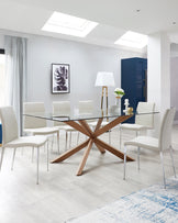 A modern dining room set featuring a rectangular glass-topped table with a unique, star-shaped wooden base, complemented by six white upholstered chairs with sleek chrome legs. A stylish floor lamp with a white shade stands in the background, adding to the contemporary aesthetic of the space.