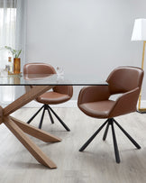 Modern dining set featuring two brown leather upholstered chairs with curved backrests and black metal legs, paired with a rectangular glass-top table with a unique angular wooden base structure. The set is displayed in a contemporary room with a light wooden floor and a white floor lamp in the background.